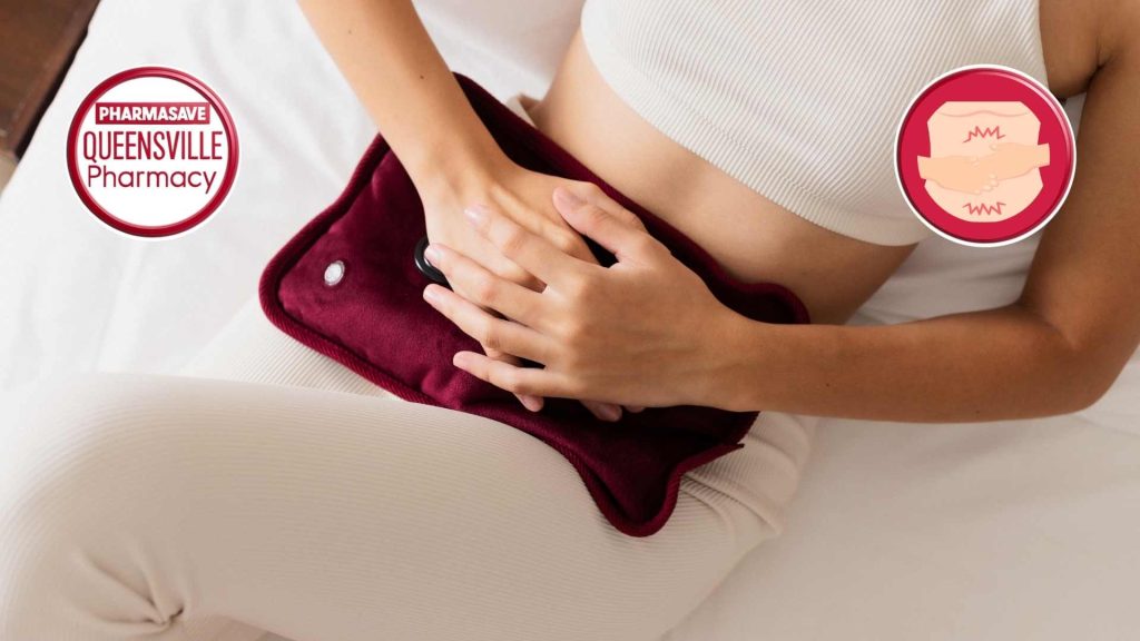 Woman sitting down, holding heating pad over belly.